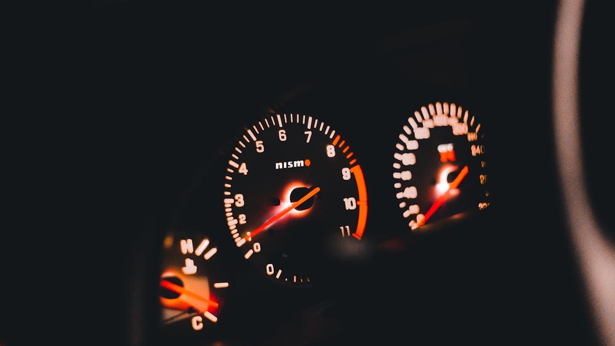 Detailed view of illuminated Nismo car gauges displaying the speedometer and tachometer.